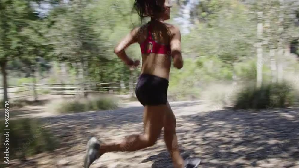 Young woman running through trees on rural road Young woman running through trees on rural road