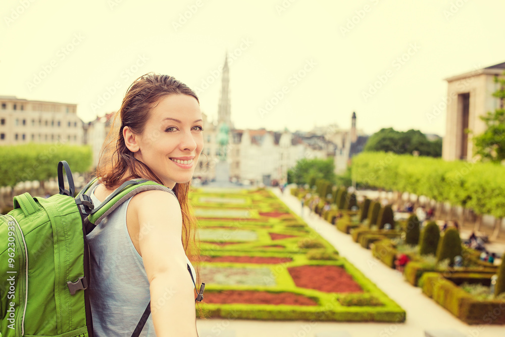 Happy woman in Brussels downtown extending you arm inviting to visit Mont des Arts garden