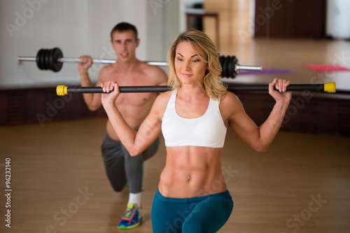 group of smiling people working out with barbells in the gym