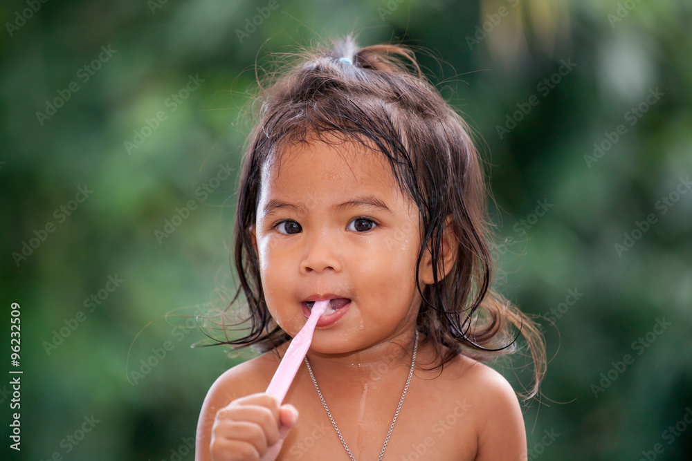 Child asian little girl brushing teeth on green background Child asian little girl brushing teeth on green background
