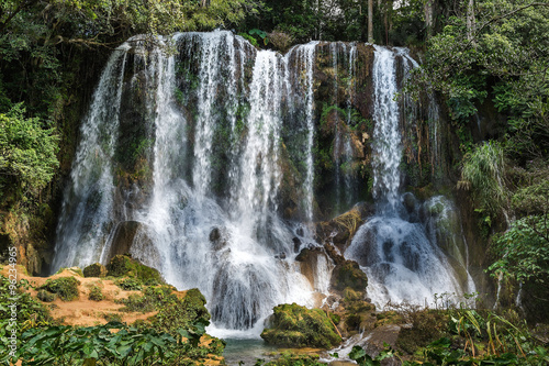 Waterfall in a lush rainforest. Beautiful waterfalls or cascades in El Nicho, El Nicho waterfall, in Scambray mountains. Cienfuegos province, Cuba. photo