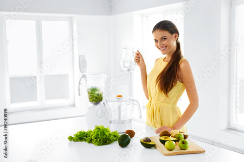 Healthy Lifestyle. Happy Smiling Vegetarian Woman Making Green Detox Vegetable Smoothie With Blender Home In Kitchen. Healthy Eating, Diet, Raw Food Concept.