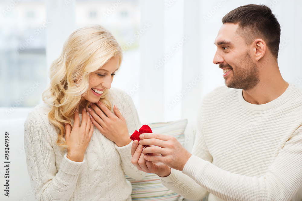 happy man giving engagement ring to woman at home