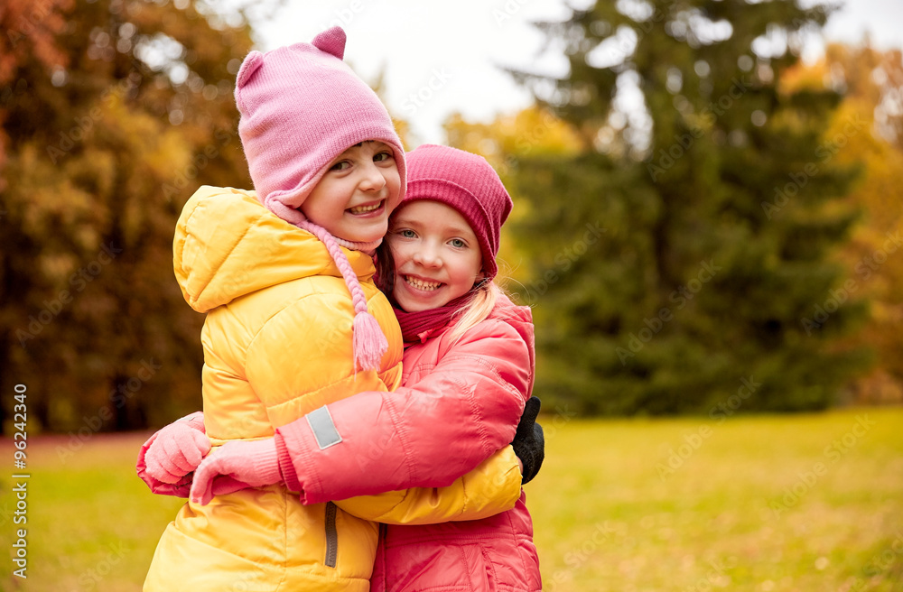 two happy little girls hugging in autumn park