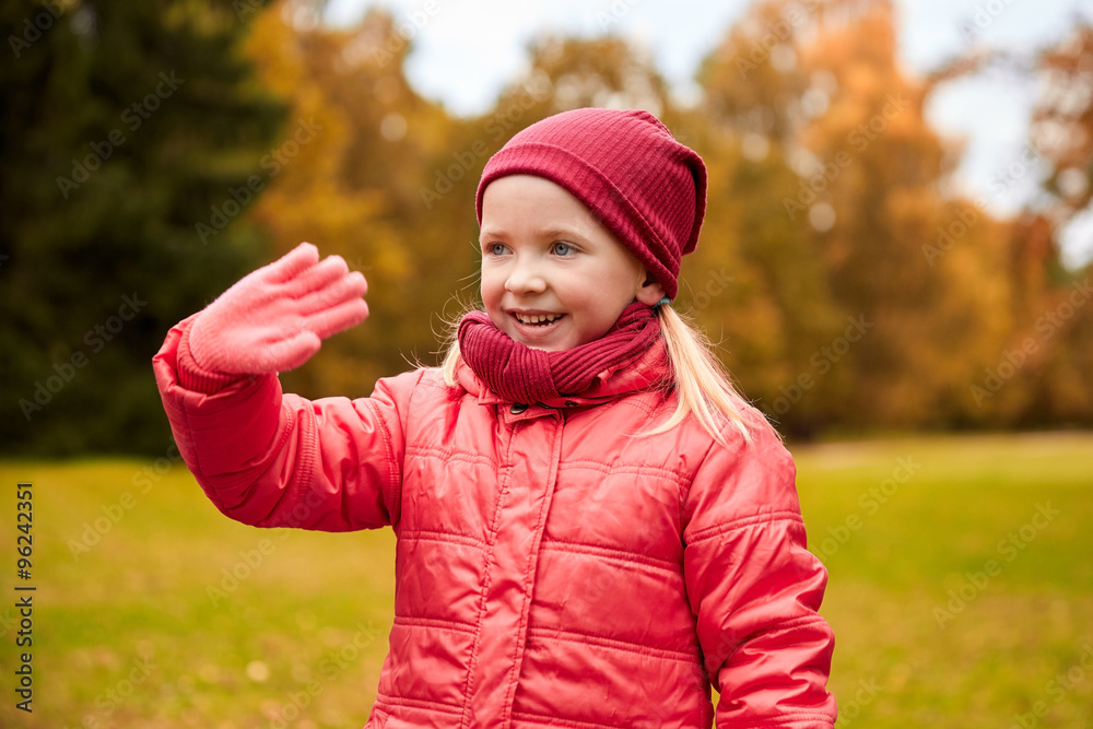happy little girl waving hand in autumn park happy little girl waving hand in autumn park
