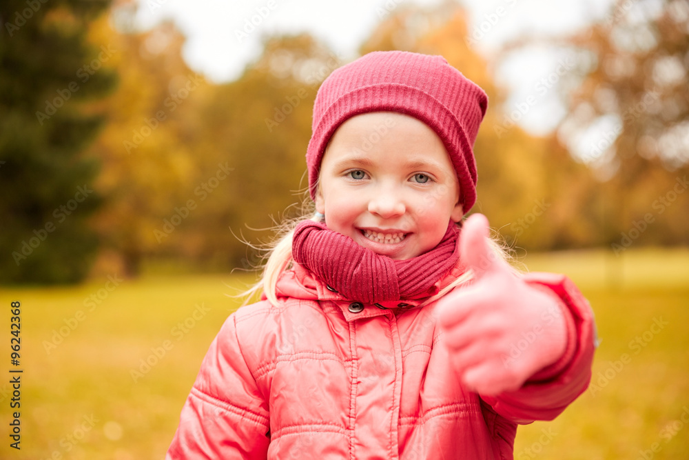 happy little girl showing thumbs up in autumn park happy little girl showing thumbs up in autumn park