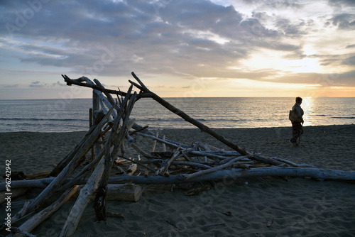 legna secca in spiaggia con donna al tramonto