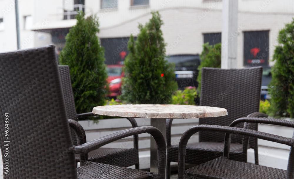 Fototapeta premium table and chairs on street cafe terrace under rain