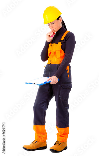 Attractive woman builder with notepad in hand, concentrate on the job, yellow helmet, orange boots and blue overalls, makes decision, positive human emotions, isolated white background.