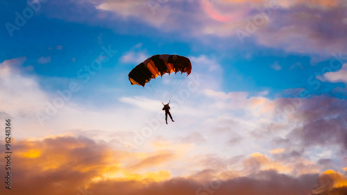 Obraz na plátně Skydiver On Colorful Parachute In Sunny Sunset Sunrise Sky