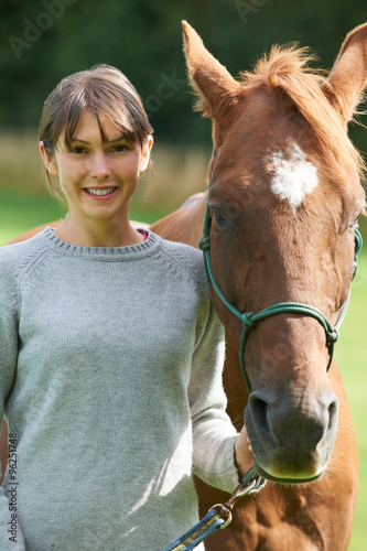 Young Woman Holding Horse In Field