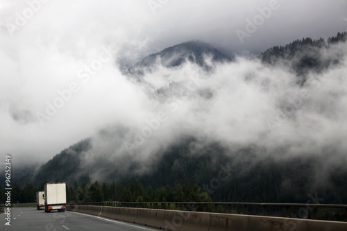 View of a mountain road in the Alps during a cloudy summer day.