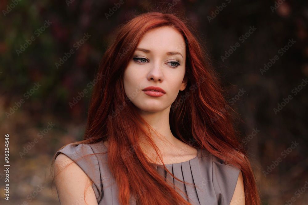 Fototapeta premium Outdoors portrait of beautiful young woman with red hair