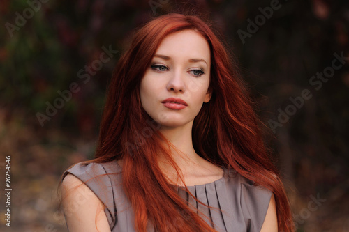 Outdoors portrait of beautiful young woman with red hair