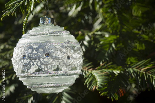 Holiday background Christmas glass ornament white vintage style hanging on a Christmas tree