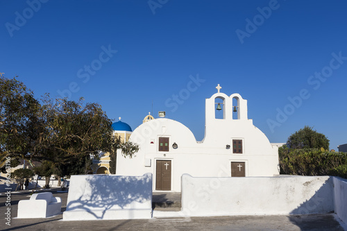 Traditional Greek white church arch with cross and bells in vill
