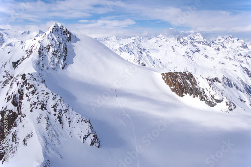 A group of skiers wandering across a glacier in Alps in Italy viewed from Austria