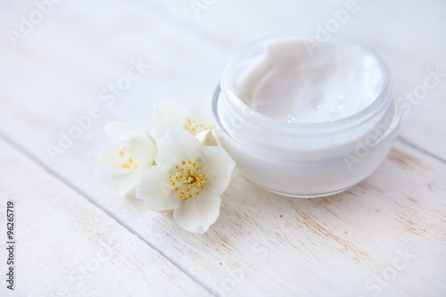 face cream with  jasmine blossom on white wooden table