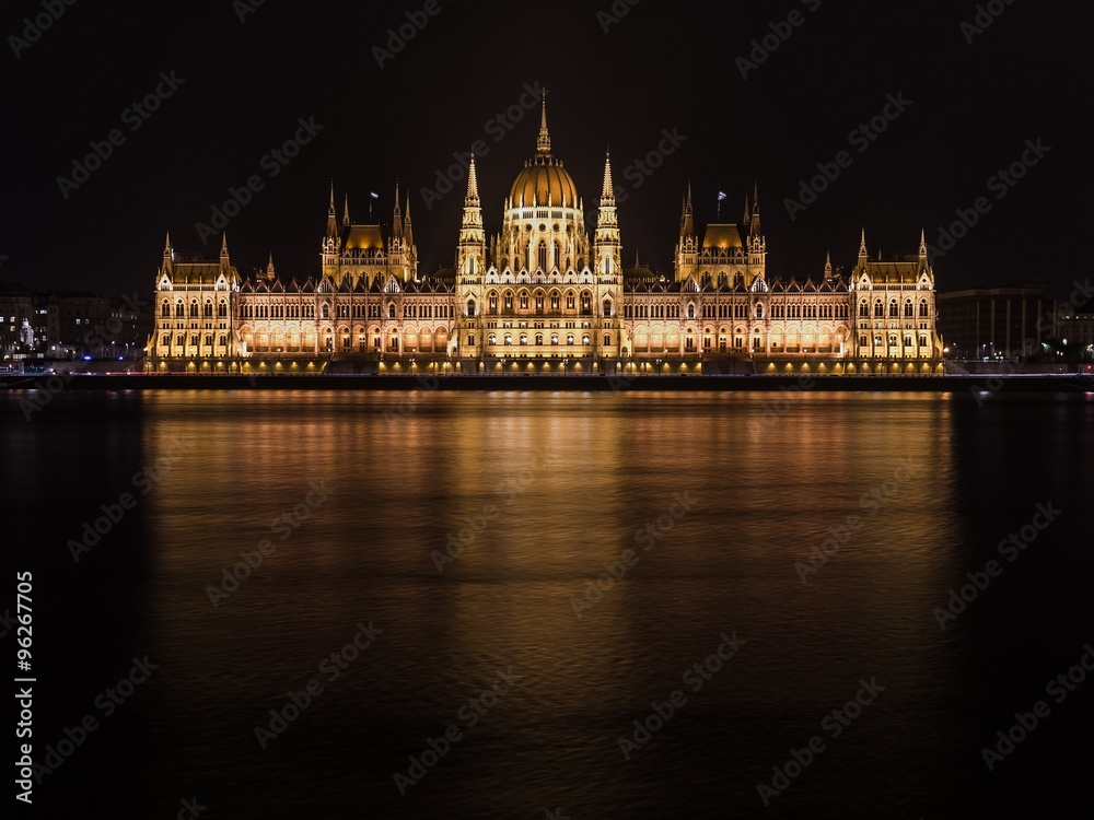 The parliament of Budapest reflecting in the Danube river at nig