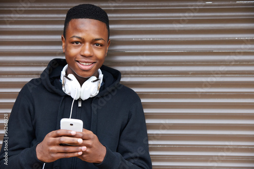 Teenage Boy Listening To Music And Using Phone In Urban Setting photo