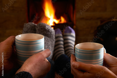Couple With Hot Drink Relaxing By Fire