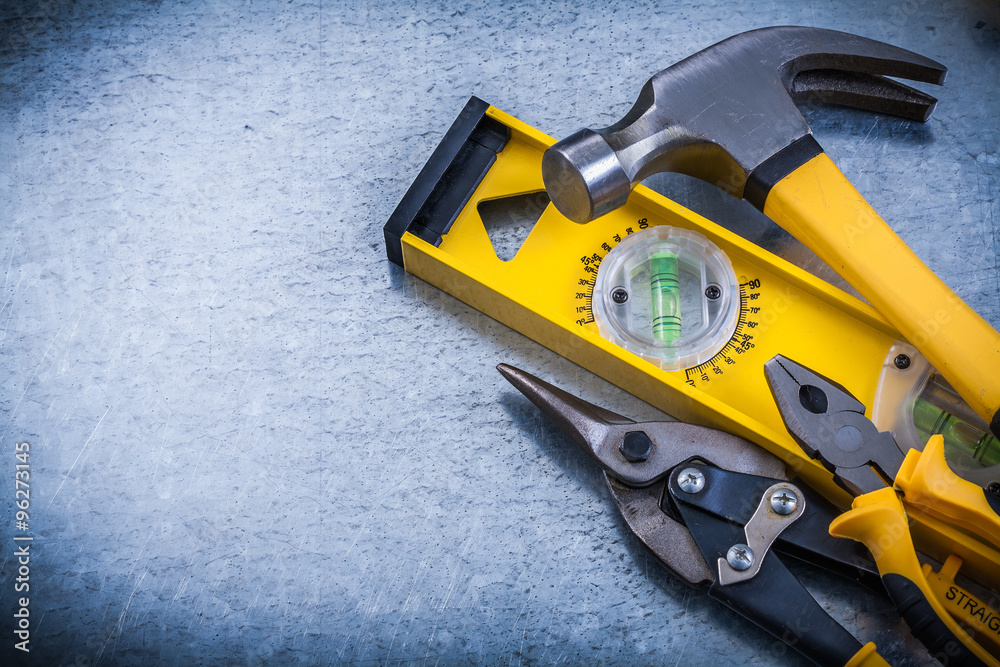 Construction level claw hammer tin snips pliers on metallic back Construction level claw hammer tin snips pliers on metallic back