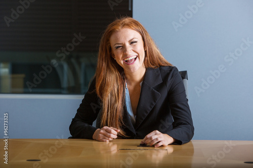 redhead business woman laughing in conference room