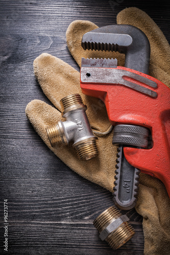 Monkey wrench plumbing fixtures protective gloves on wooden boar