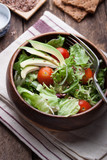 .Salad with lettuce, tomatoes, flax seeds and avocado in a wooden bowl.