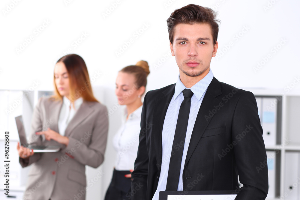 Cheerful business man in office with colleagues in the background, sturt up team Cheerful business man in office with colleagues in the background, sturt up team