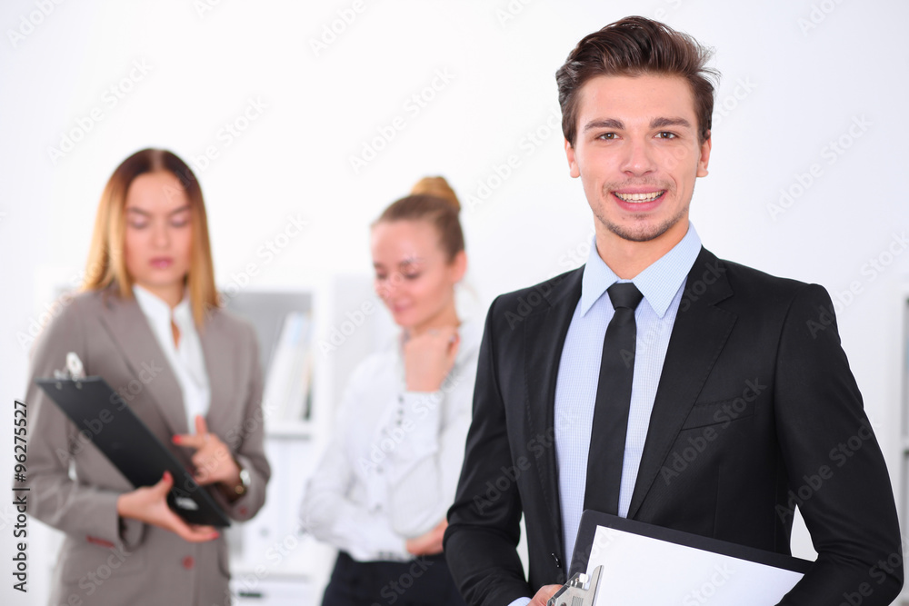 Cheerful business man in office with colleagues in the background, sturt up team Cheerful business man in office with colleagues in the background, sturt up team