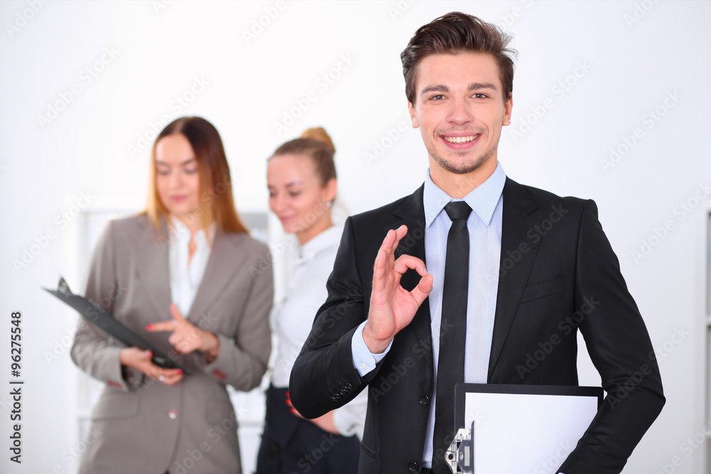 Cheerful business man in office with colleagues in the background, sturt up team Cheerful business man in office with colleagues in the background, sturt up team