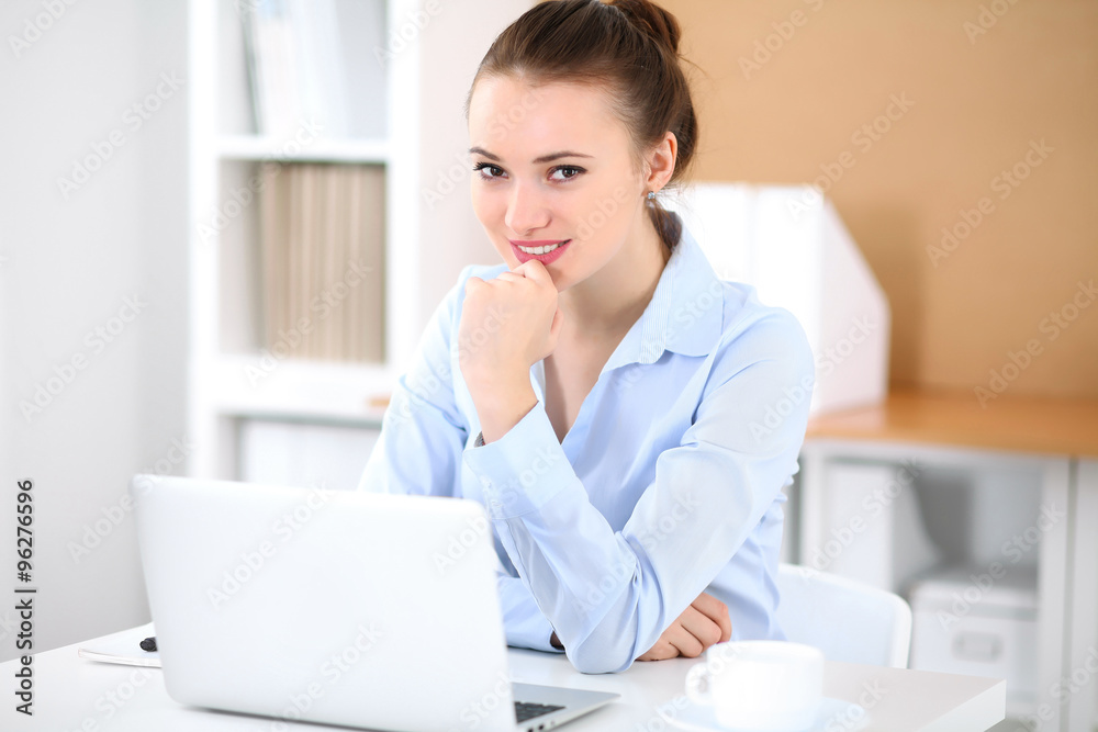 Young business woman working on laptop in office. Successful business concept. Young business woman working on laptop in office. Successful business concept.