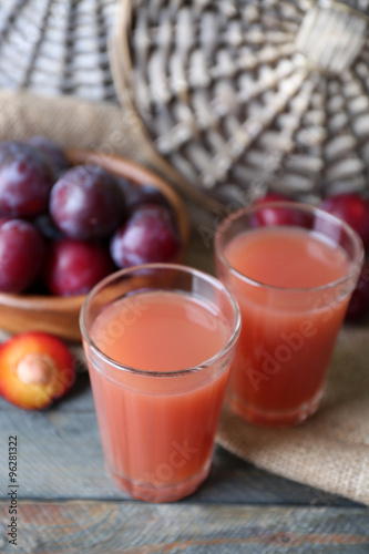 Delicious plum juice with fruits on wooden table close up