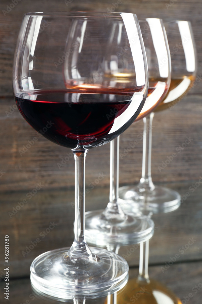 Glasses with white, rose and red wine on wooden background, close up
