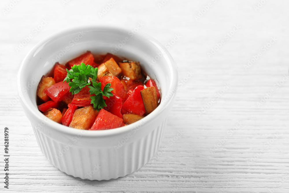 Tasty vegetarian ratatouille made of eggplants, squash, tomatoes in bowl on wooden table background Tasty vegetarian ratatouille made of eggplants, squash, tomatoes in bowl on wooden table background