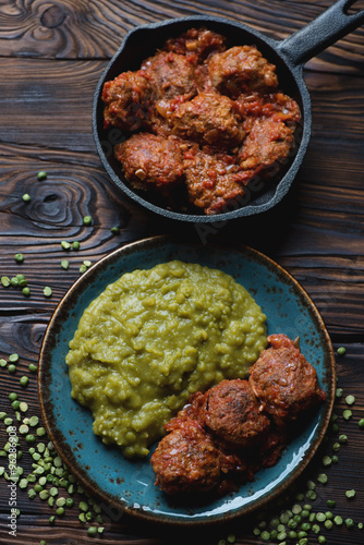 Top view of meatballs in tomato sauce with boiled green peas