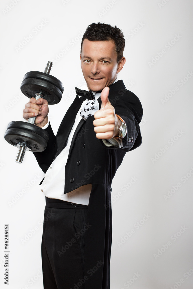 Man in tuxedo holds dumbell. Man in tuxedo holds dumbell.