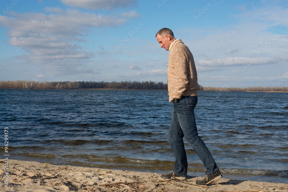 Happy man, wearing casually, walking along the coast , thinking