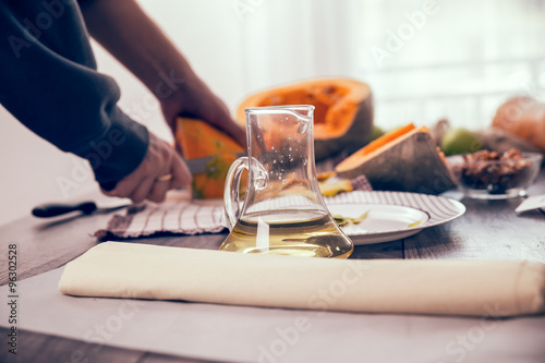 Woman in kitchen making prepares a pie with pumpkin, selective focus