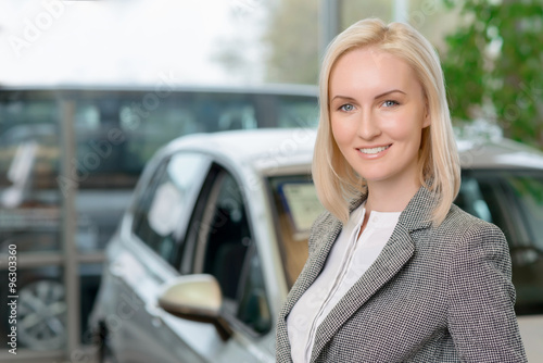 Female customer is standing in front of a car. 