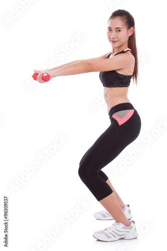Full length of young woman doing exercise with lifting weights