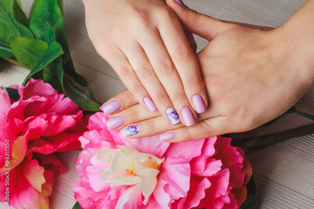 Fototapeta premium Lilac nail art with printed flowers on light background