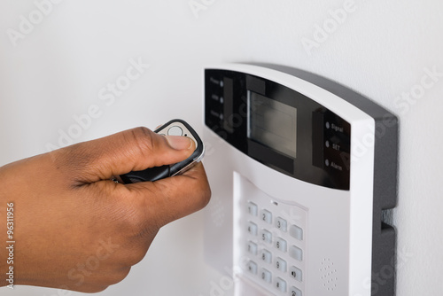 Person's Hand Using Remote To Operate Entrance Security System