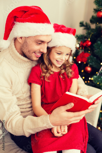 smiling father and daughter reading book