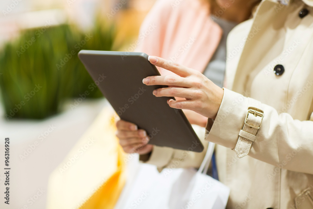 close up of women with tablet pc and shopping bags