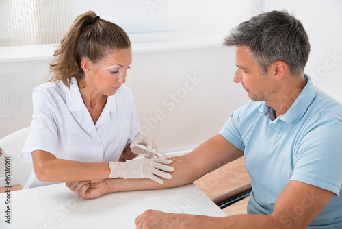 Doctor Drawing Blood From Patient With Syringe
