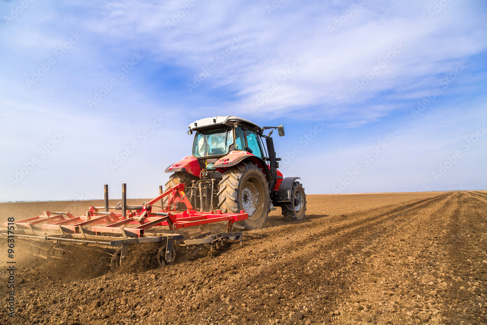 Fototapeta premium Farmer in tractor preparing land with seedbed cultivator