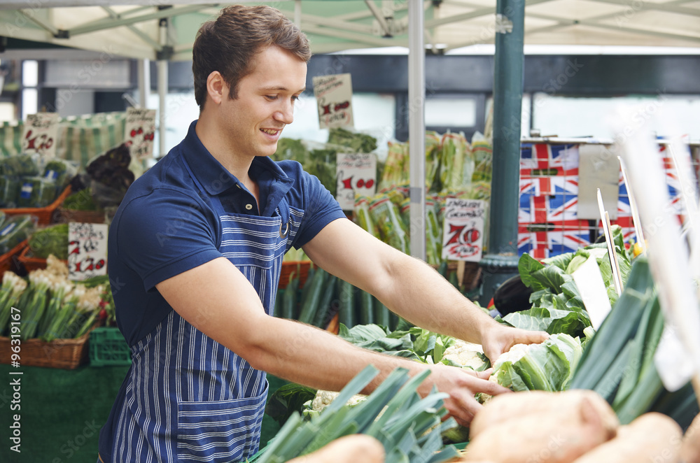 Obraz premium Man Arranging Display On Market Vegetable Stall