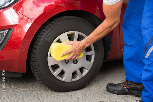 Worker Cleaning Car Wheel With Sponge